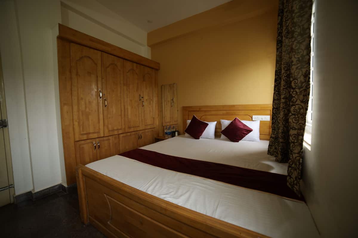 Ein Hotelzimmer mit einem Holzbett, einem Kleiderschrank und einem Fenster mit gemusterten Vorhängen.