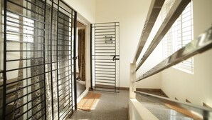 Un escalier avec une rampe en métal, un tapis à motifs au pied de l’escalier et une porte avec un portail en métal.