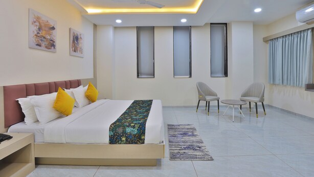 Una habitación de hotel moderna con cama, mesita de noche, silla y una pequeña mesa.