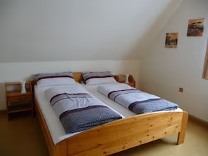 Un lit double avec un cadre en bois, deux tables de chevet et une petite table de nuit.