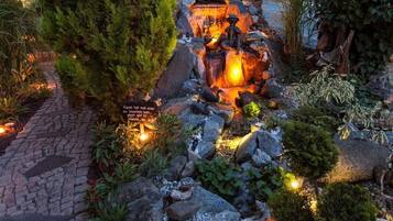 Un jardin avec un sentier en pierre, une petite cascade et un panneau avec du texte.