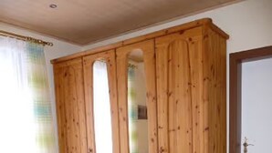 A bedroom with a wooden wardrobe, a bed with an orange bedspread, and a wooden floor. - Apartment 'Wassergartenparadies' with Shared Terrace, Shared Garden and Wi-Fi (Harsdorf)