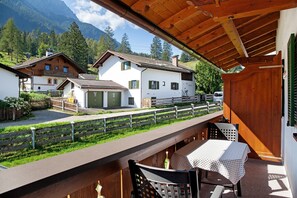 Un balcon avec une table et des chaises, donnant sur un paysage montagneux parsemé de maisons.
