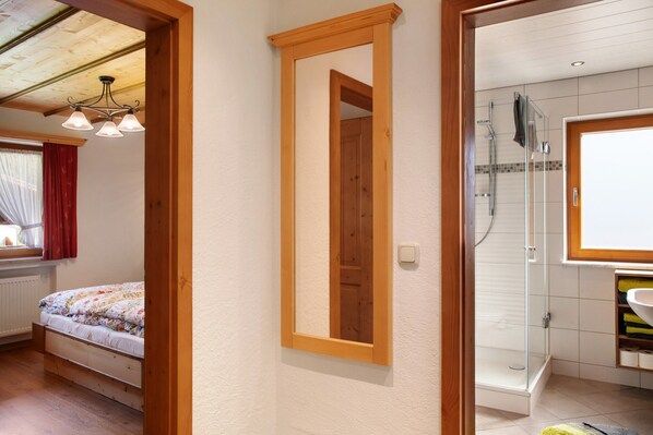 A bedroom with a bed, a mirror, and a bathroom with a shower and sink. - Apartment 'Ferienwohnung Waxensteinblick' with Mountain View, Balcony and Wi-Fi (Grainau)