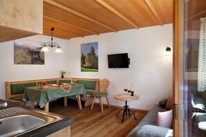 Un coin repas accueillant avec une table en bois, des bancs et une petite table ronde où sont disposées des boissons.