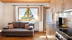 A modern kitchen with wooden cabinets, a built-in oven, and a window with curtains. - Apartment 'Ferienwohnung Waxensteinblick' with Mountain View, Balcony and Wi-Fi (Grainau)