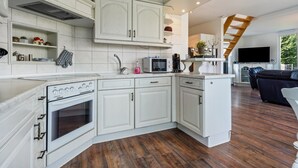 A modern kitchen with white cabinetry, a built-in oven, a microwave, and a coffee maker. - Holiday Home 'Sonja' with Private Terrace, Wi-Fi and Air Conditioning (Lichtenwalde)