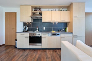 Una cocina moderna con armarios de madera, horno empotrado, lavavajillas y cafetera.