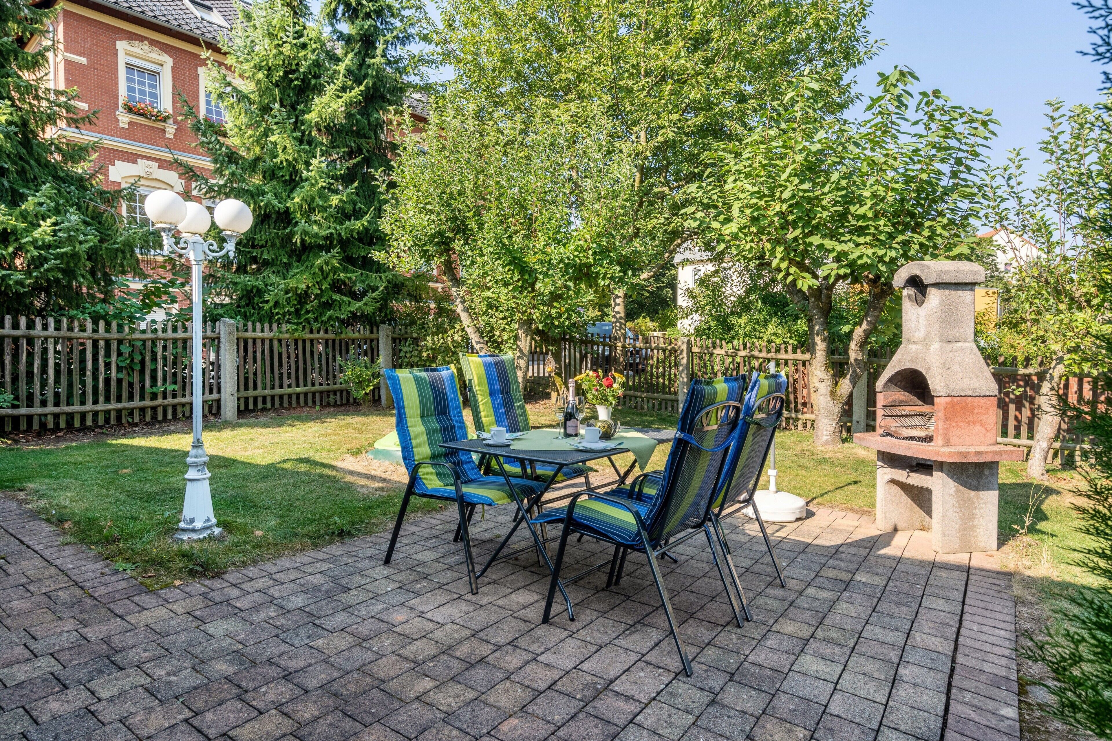 A patio with a table and chairs, a stone oven, and a fence.