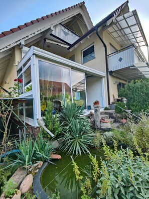 A house with a covered patio, a garden with a pond, and a red flower. - Apartment 'Ferienwohnung Susi' with Mountain View, Balcony and Wi-Fi (Oberkirch)