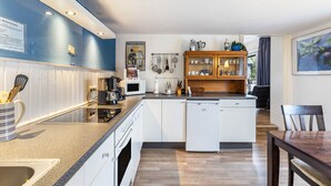 Une cuisine moderne avec des meubles blancs, un four encastré et une machine à café.