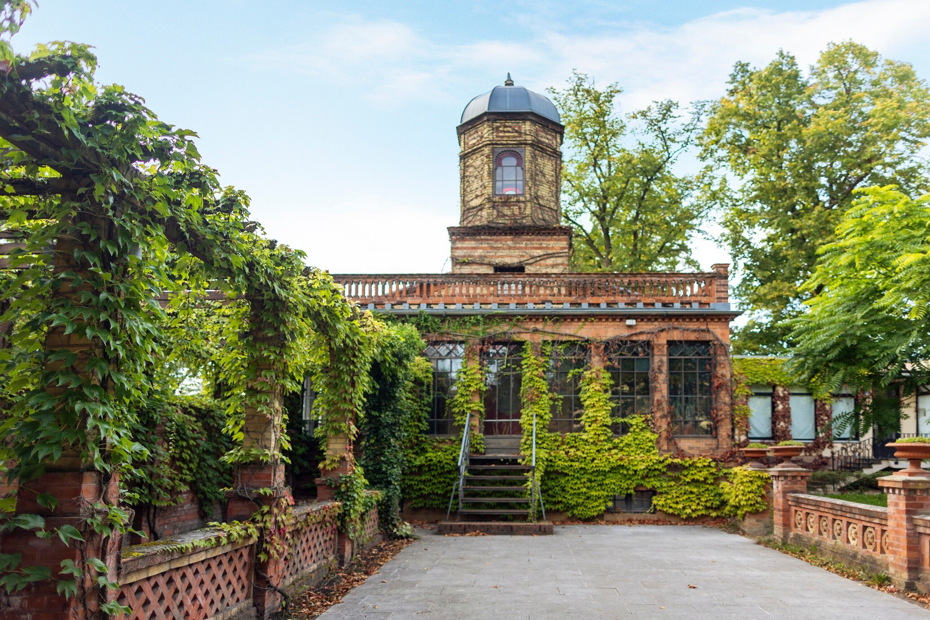 A historic building with a tower, ivy-covered walls, and a central staircase.