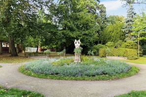 A garden with a central statue, surrounded by a circular path and various plants. - Apartment 'Innenstadt Quartier' (Neuruppin)