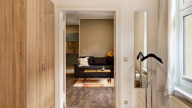 Un pasillo que conduce a una sala de estar con un sofá, una mesa de centro y un espejo.