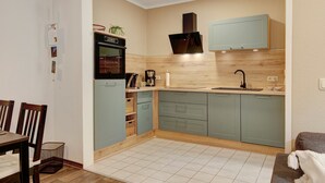 Cocina compacta con estufa, pileta y alacenas, un comedor con sillas y un pequeño sofá.