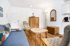 A room with a sofa, a wooden table, a chair, a cabinet, and a mirror. - Apartment 'Haus Baltic - Ferienwohnung 29' with Balcony and Wi-Fi (Sellin)