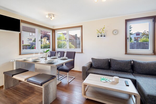 Una sala de estar moderna con comedor, sofá, una mesa de centro y vistas al exterior.