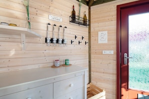 Interior de madera con mostrador blanco, botellas de vino y una puerta roja.