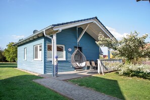 Ett blått hus med en veranda, en hängstol och en liten trädgård.