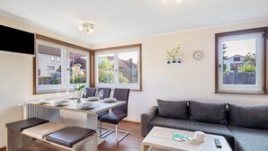 Una sala de estar moderna con comedor, sofá, una mesa de centro y vistas al exterior.