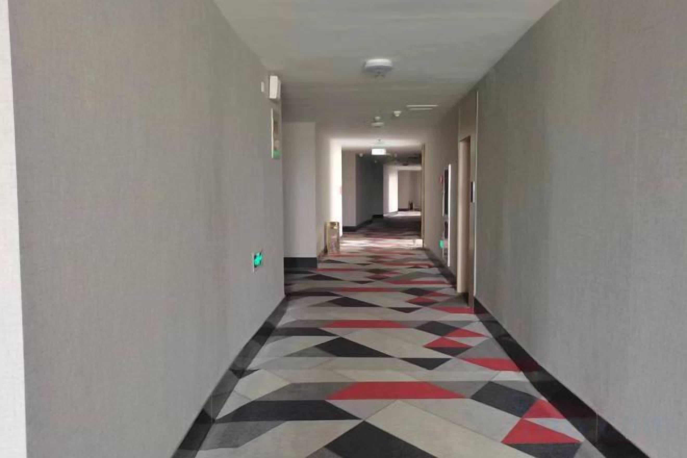A hallway with patterned flooring and doors on both sides.