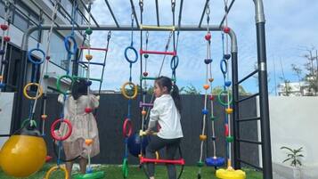 An outdoor play area with a climbing structure and swings.