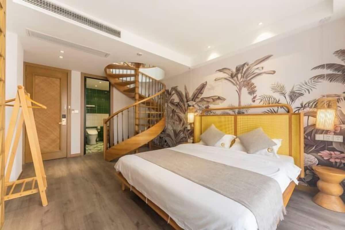 A bedroom with a wooden bed, a spiral staircase, and a tropical-themed wall mural.