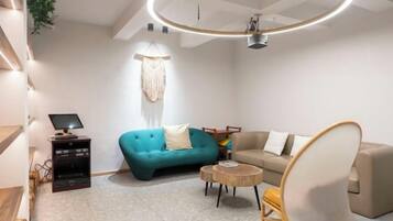 A modern living room with a teal sofa, a beige sofa, a round coffee table, and a unique chair.