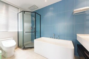 Un bagno moderno con cabina doccia in vetro, una vasca da bagno freestanding e un water bianco.