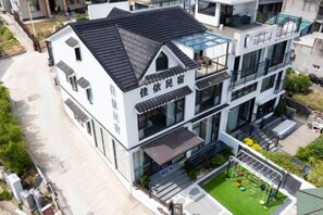 A multi-story building with a flat roof, large windows, and a visible outdoor area with greenery. - Xiangshan Jiayi Sisters Holiday Villa (Xiangshan)
