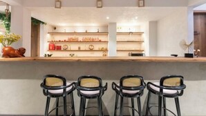 A bar area with a wooden counter, three black bar stools, and shelves with bottles and decorative items. - Xiangshan Jiayi Sisters Holiday Villa (Xiangshan)