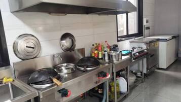 Een professionele keuken met roestvrijstalen apparatuur, een afzuigkap en een raam.