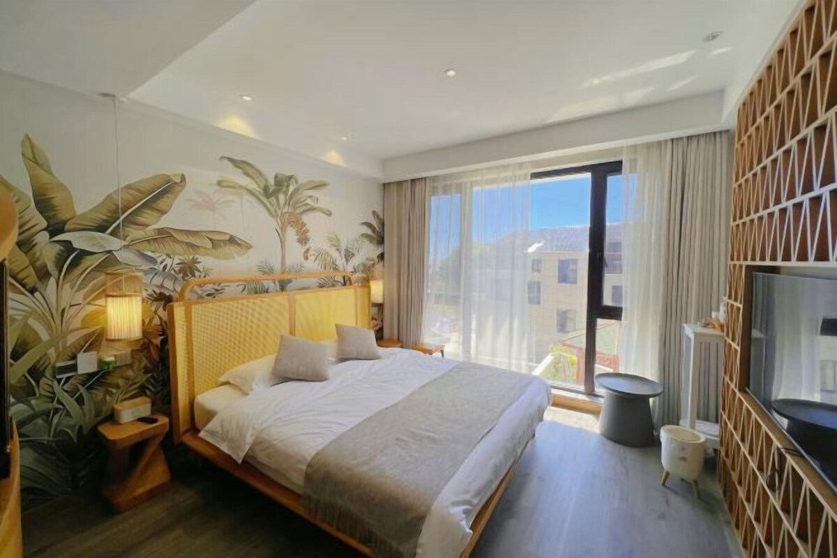 Una camera d'albergo moderna con un letto grande, una TV e un balcone con vista sugli edifici.