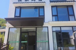 A hotel entrance with a covered awning, large windows, and a visible door. - Xiangshan Jiayi Sisters Holiday Villa (Xiangshan)