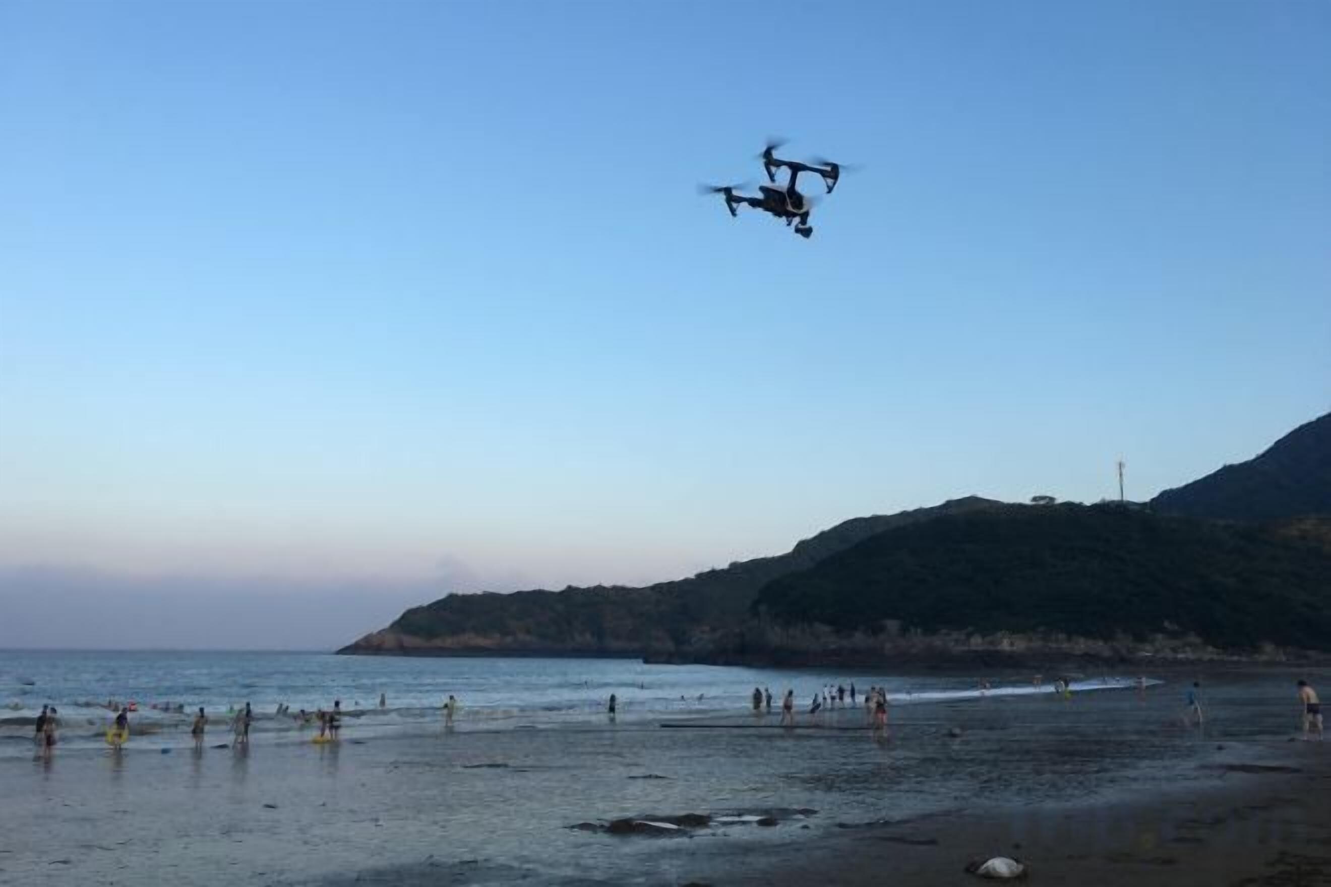 Une plage avec un drone qui vole au-dessus.