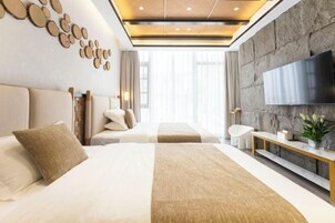 Una habitación de hotel moderna con una cama grande, una mesita de noche, un televisor y una pared decorativa de piedra.
