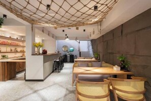 Interior de un restaurante con barra, mesas y una escalera que sube a un nivel superior.