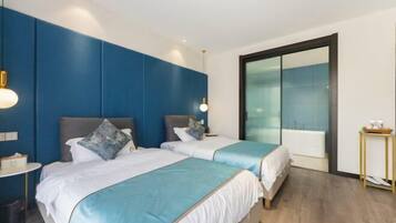 Quarto de hotel moderno com duas camas, um espelho grande e uma mesinha de cabeceira com abajur.