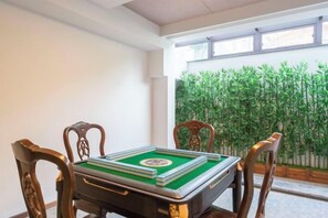 A room with a table set for a game, wooden chairs, and a view of greenery through a window. - Xiangshan Jiayi Sisters Holiday Villa (Xiangshan)