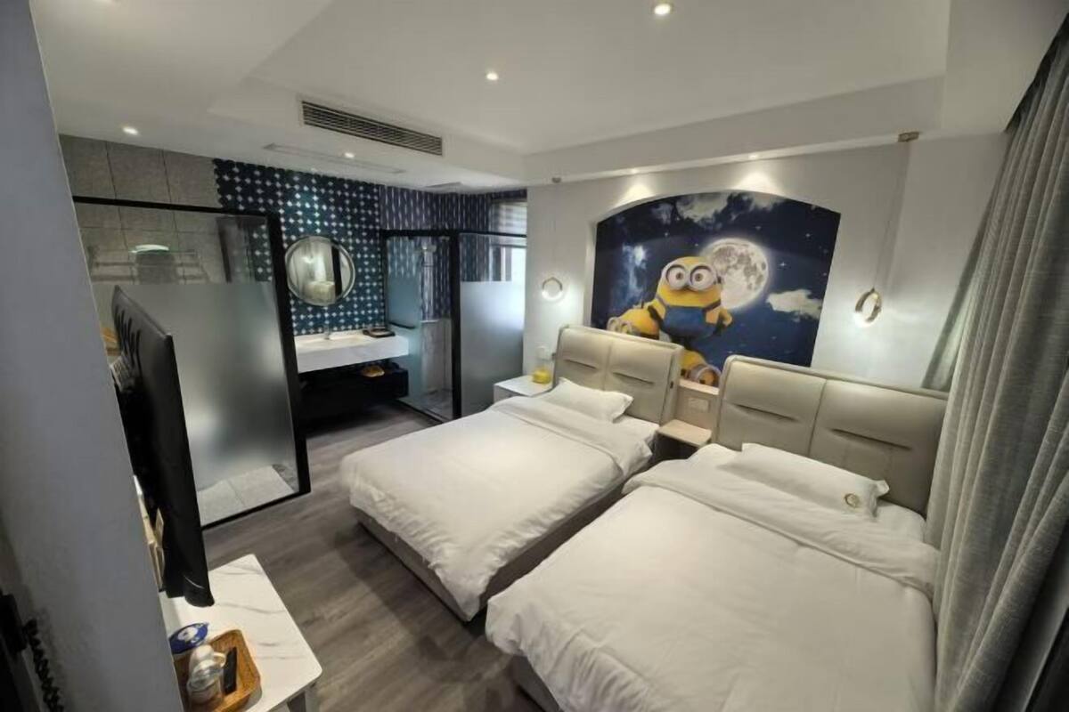 A hotel room with two beds, a TV, a mirror, a night sky mural, and a window with curtains.