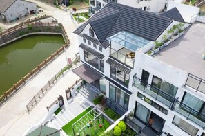 A modern multi-story building with a flat roof, large windows, and a small courtyard with a pond. - Xiangshan Jiayi Sisters Holiday Villa (Xiangshan)