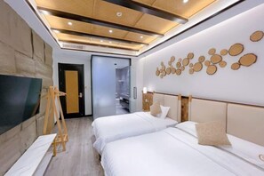 Camera d'albergo con due letti, una scala in legno, una TV a schermo piatto e una parete con decorazioni circolari.