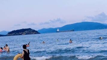 Massa de água com pessoas nadando e uma ilha ao longe.