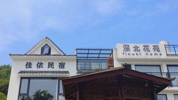 Een gebouw met een bord waarop 'flower home' staat en een ander bord met de tekst '佳依民宿'.