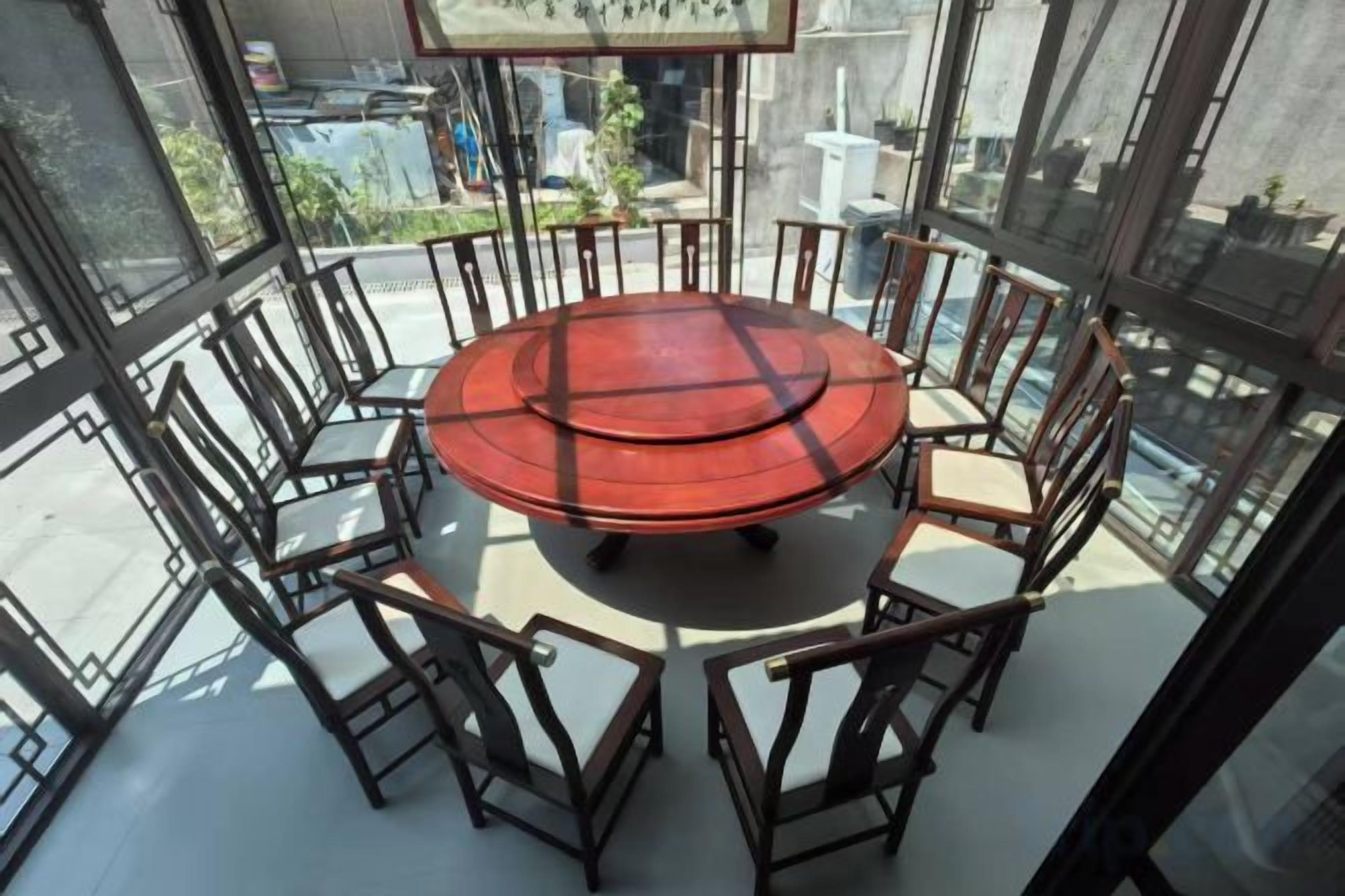 A round table with chairs in a room with large windows.