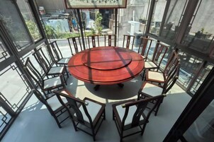 Una mesa redonda con sillas en una habitación con ventanas amplias.