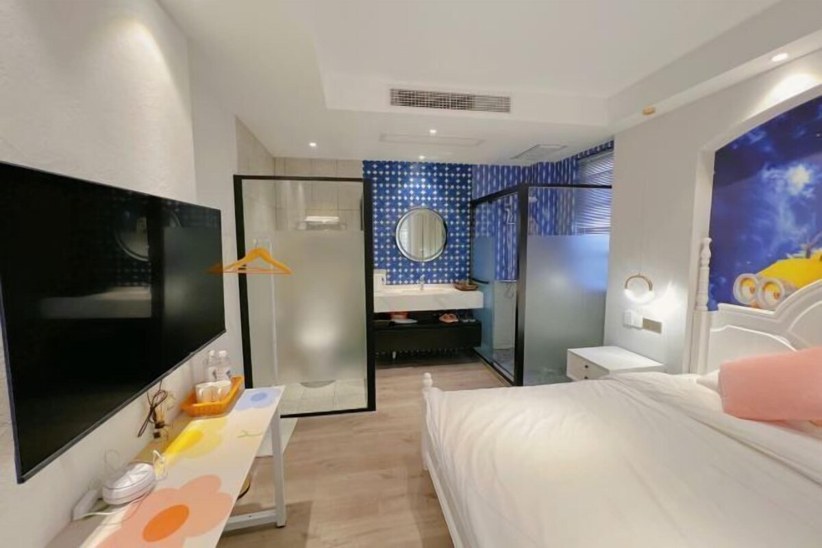 Camera d'albergo con un letto, una TV, uno specchio, un bagno con doccia e un affresco raffigurante il cielo notturno.
