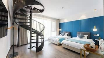 A modern bedroom with a spiral staircase, two beds, and a blue accent wall.