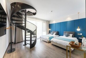 Un dormitorio moderno con una escalera espiral, dos camas y una pared de acento azul.