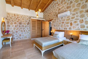 Quarto com parede de pedra, teto de madeira e cama com estrutura de madeira.